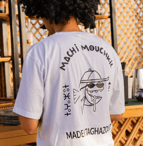 The white Machi Mouchkil tee from behind, hand-drawn fish print above 'Made in Taghazout'